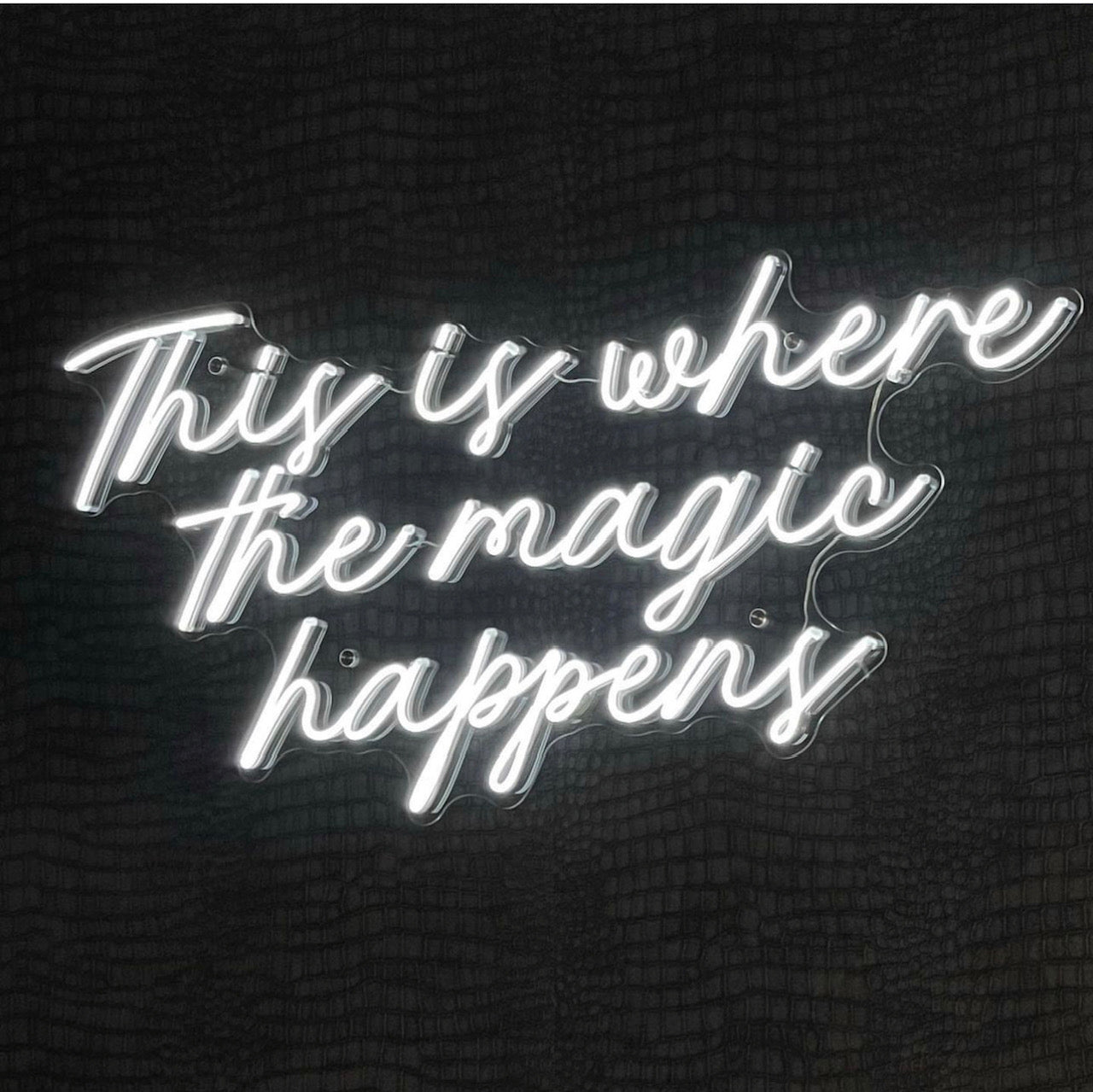 Creative studio neon sign reading 'This is where the magic happens', setting an inspiring ambiance.
